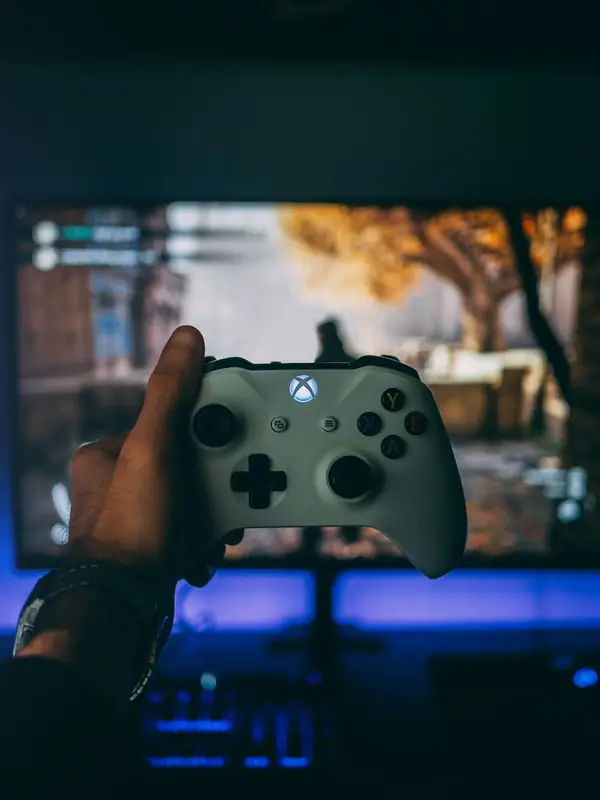Manette Xbox tenue en main devant un jeu