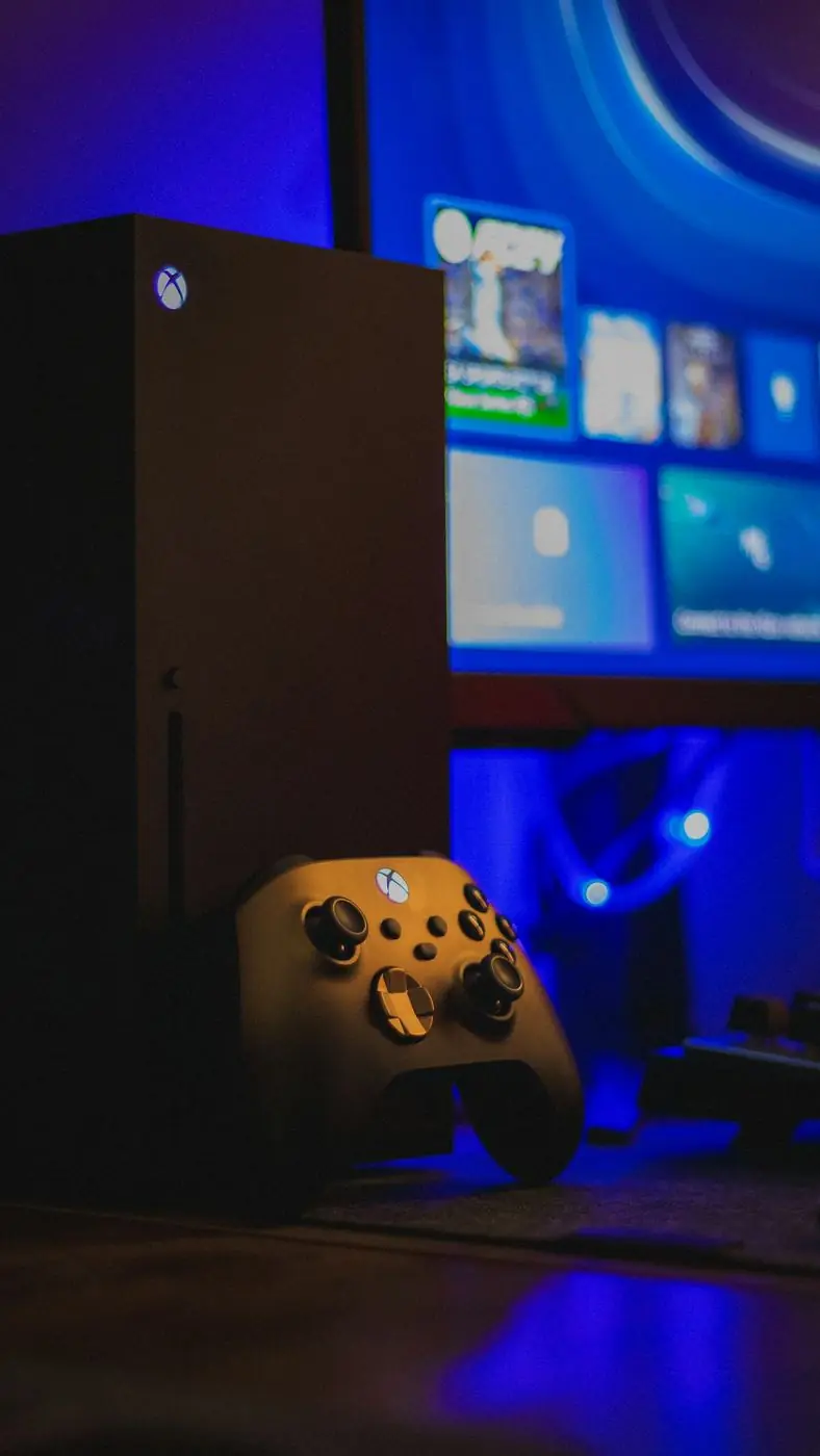 Console Xbox Series X et sa manette dans une pièce éclairée en bleu